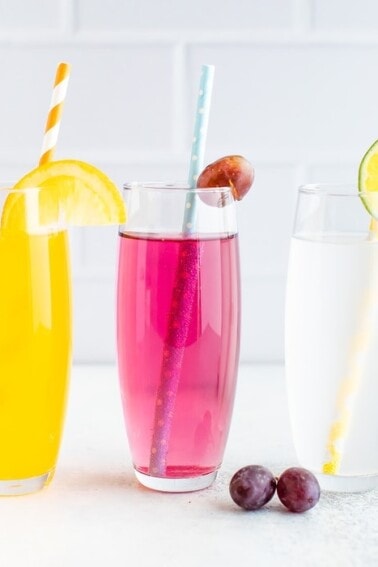 Three glasses of homemade different flavor soda with paper straws.