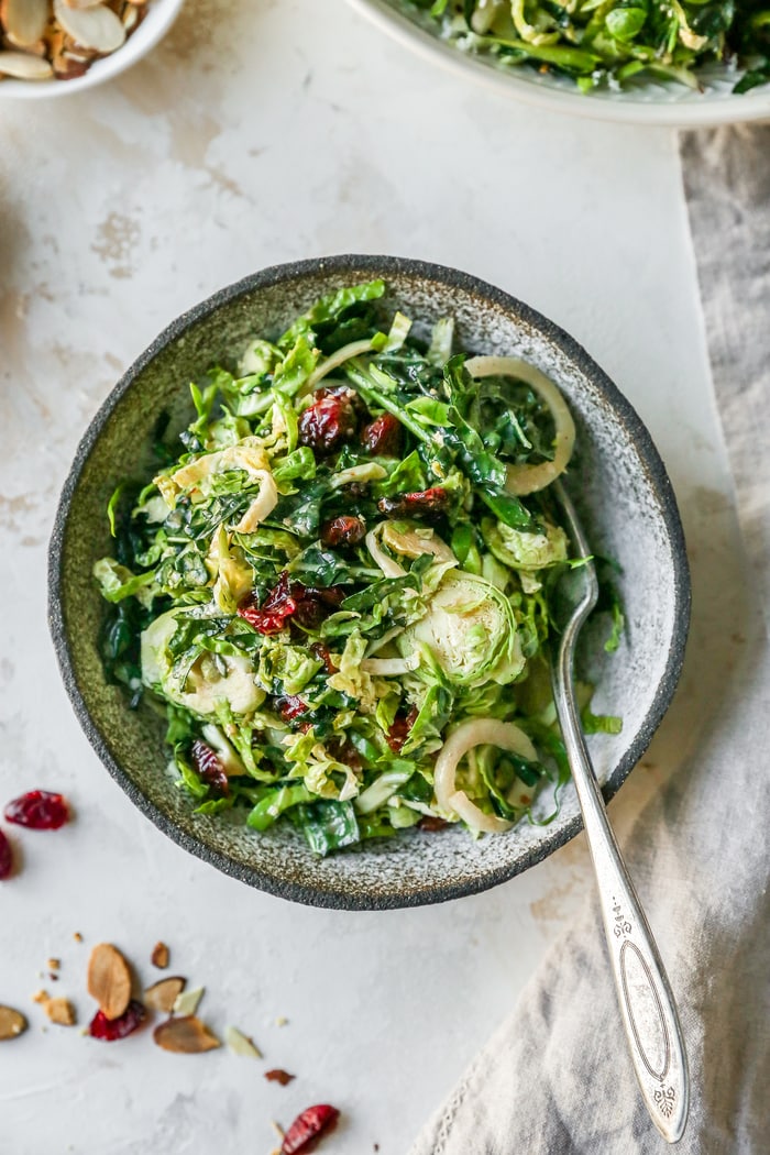 Bowl with kale, brussels with cranberries and almonds salad. Silver fork is in the bowl.