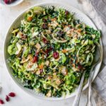 Kale and brussels sprout salad in a bowl with serving spoons.