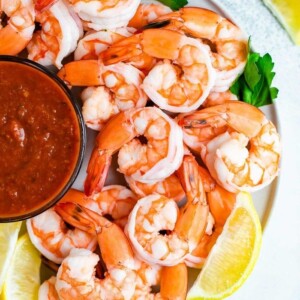 Plate with shrimp cocktail garnished with parsley and lemon.