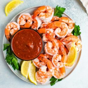 Plate with shrimp cocktail garnished with parsley and lemon.