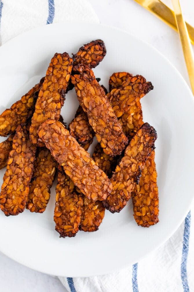 Crispy slices of tempeh bacon on a plate.