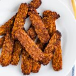 Crispy slices of tempeh bacon on a plate.