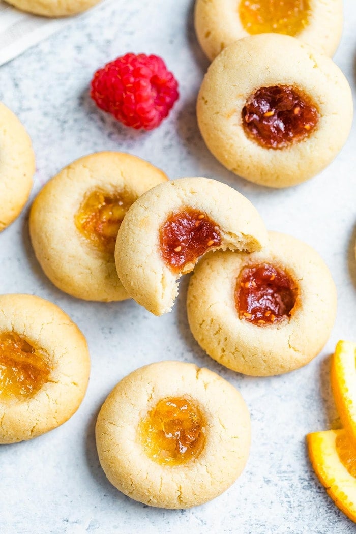 Almond flour thumbprint cookies with a bite out of one. Some have raspberry jam and some have orange marmalade.