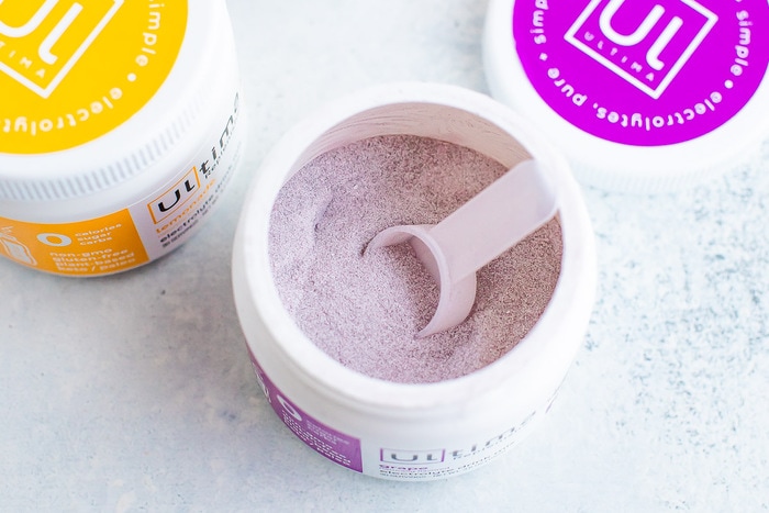 Little scooper in a jar of grape electrolyte powder.