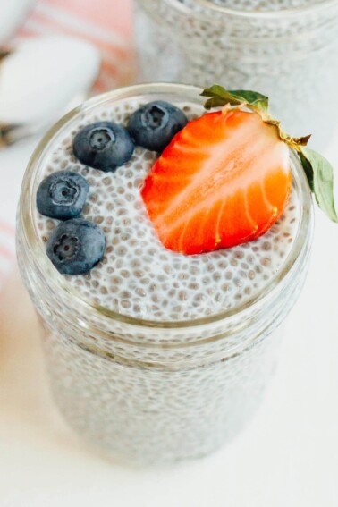 Jar with chia pudding topped with a strawberry and blueberries.