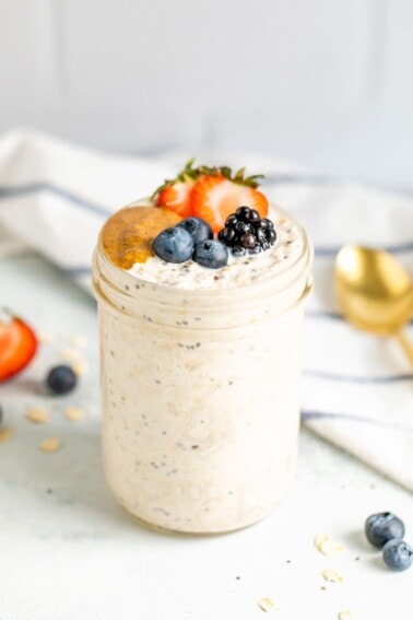 Jar of overnight oats topped with berries and nut butter.