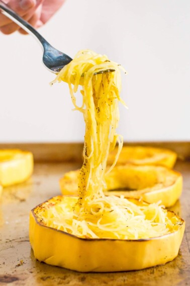Fork picking up spaghetti squash from a cooking sheet.