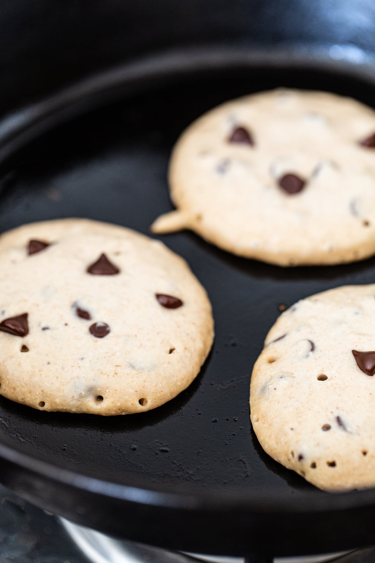 Chocolate chip pancakes in a frying pan.