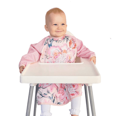 Toddler sitting in high chair wearing a pink bib with long sleeves that covers their lap