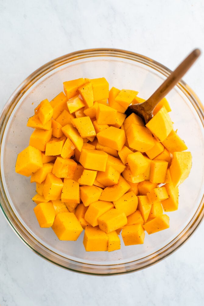 Bowl full of cubed butternut squash. A spoon is in the bowl.