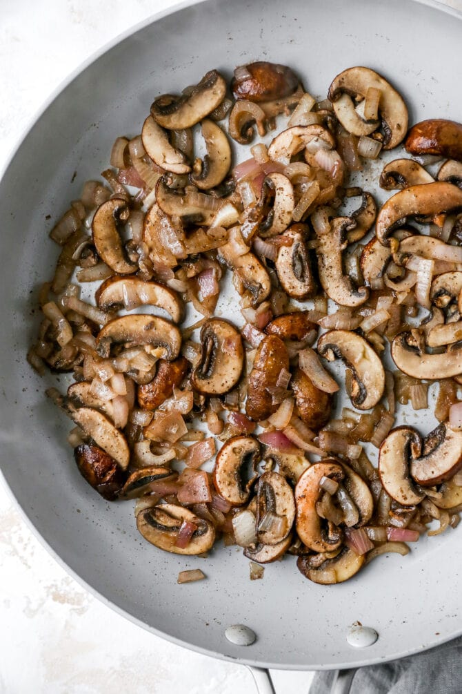 Sautéed mushrooms and onions in a pan.