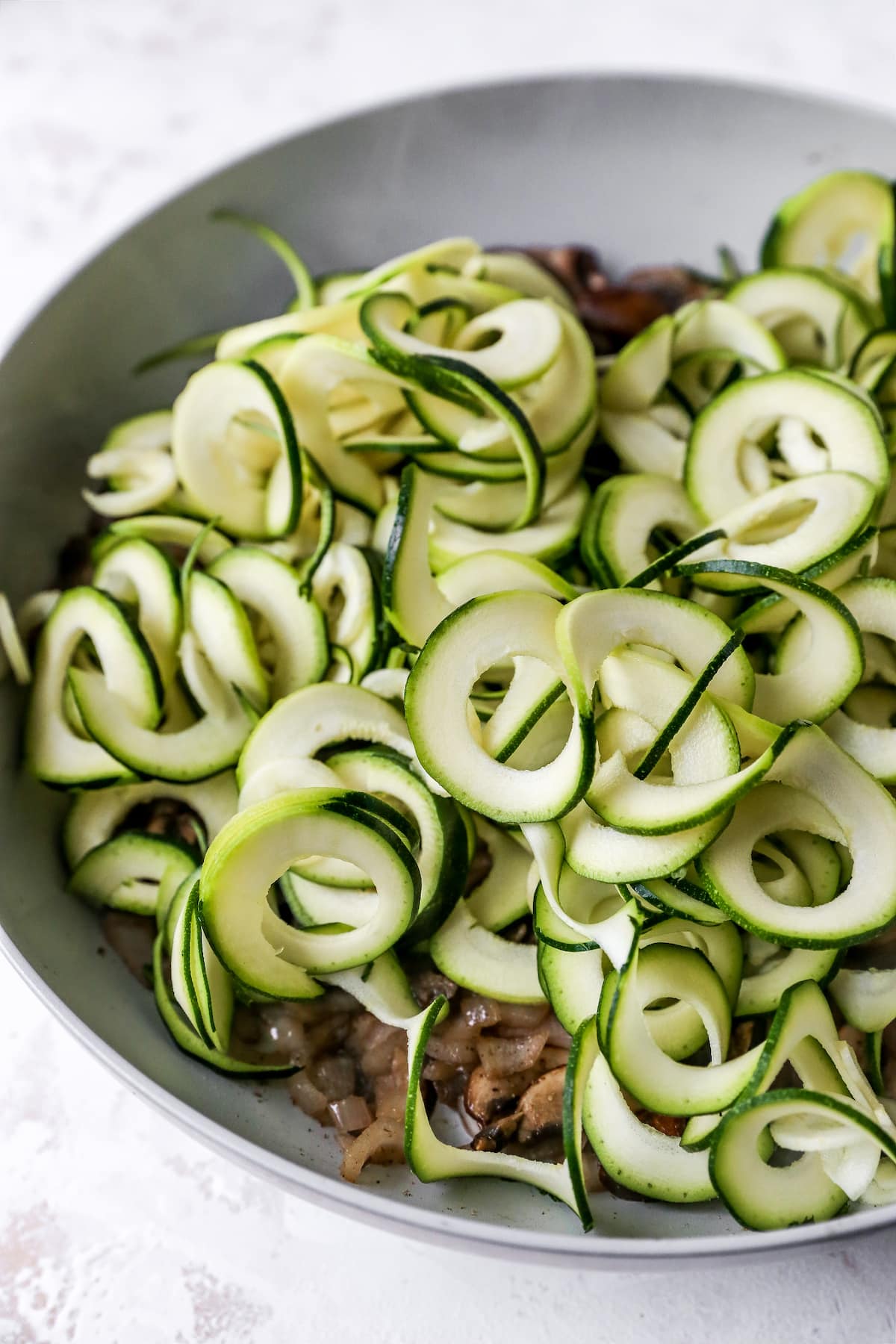 Zucchini noodles and mushrooms in a pan.