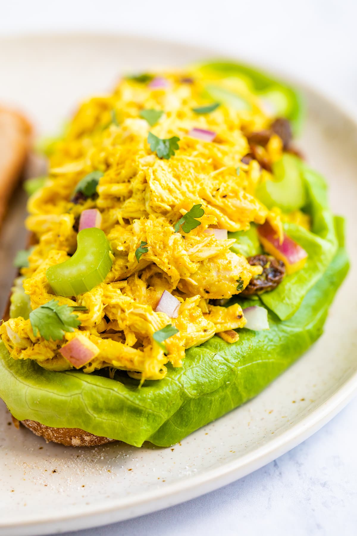 Close up of curry chicken salad on an open faced sandwich with sourdough bread.