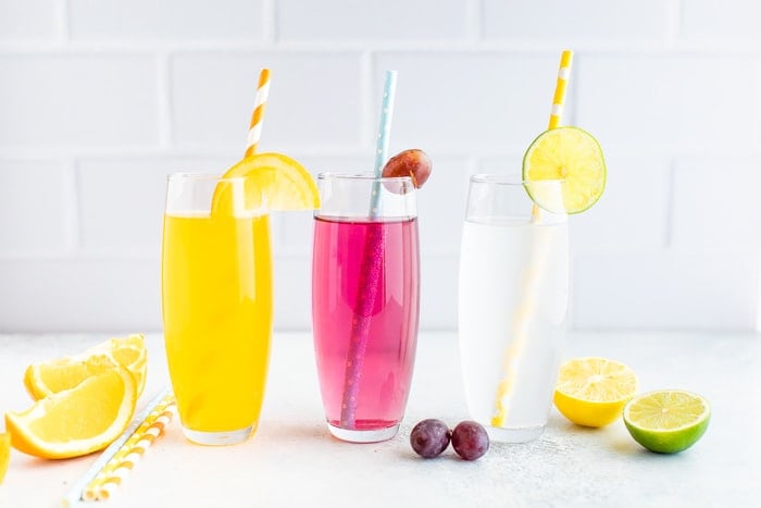 Three glasses of homemade different flavor soda with paper straws.