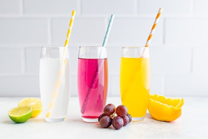 Three glasses of homemade different flavor soda with paper straws.