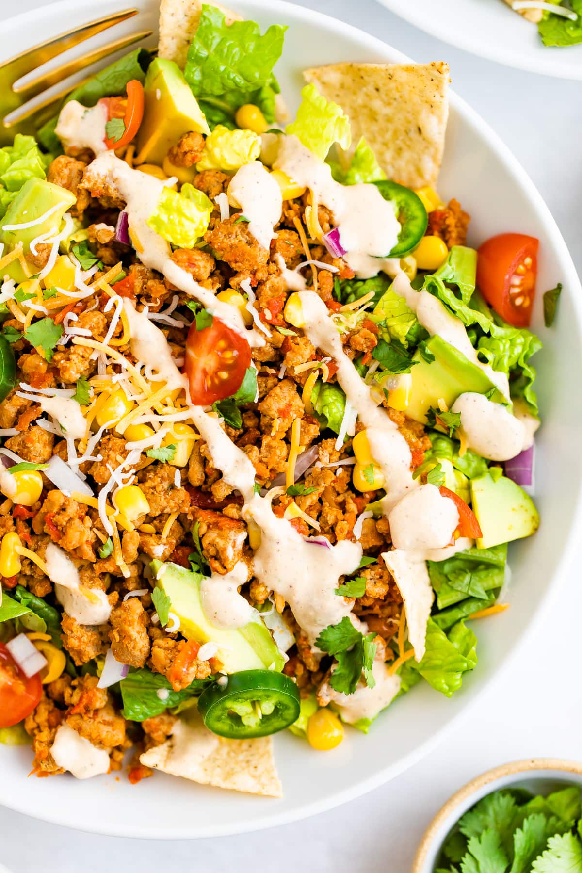 Taco salad topped with ground turkey, avocado, corn, peppers, chips, dressing and tomatoes.