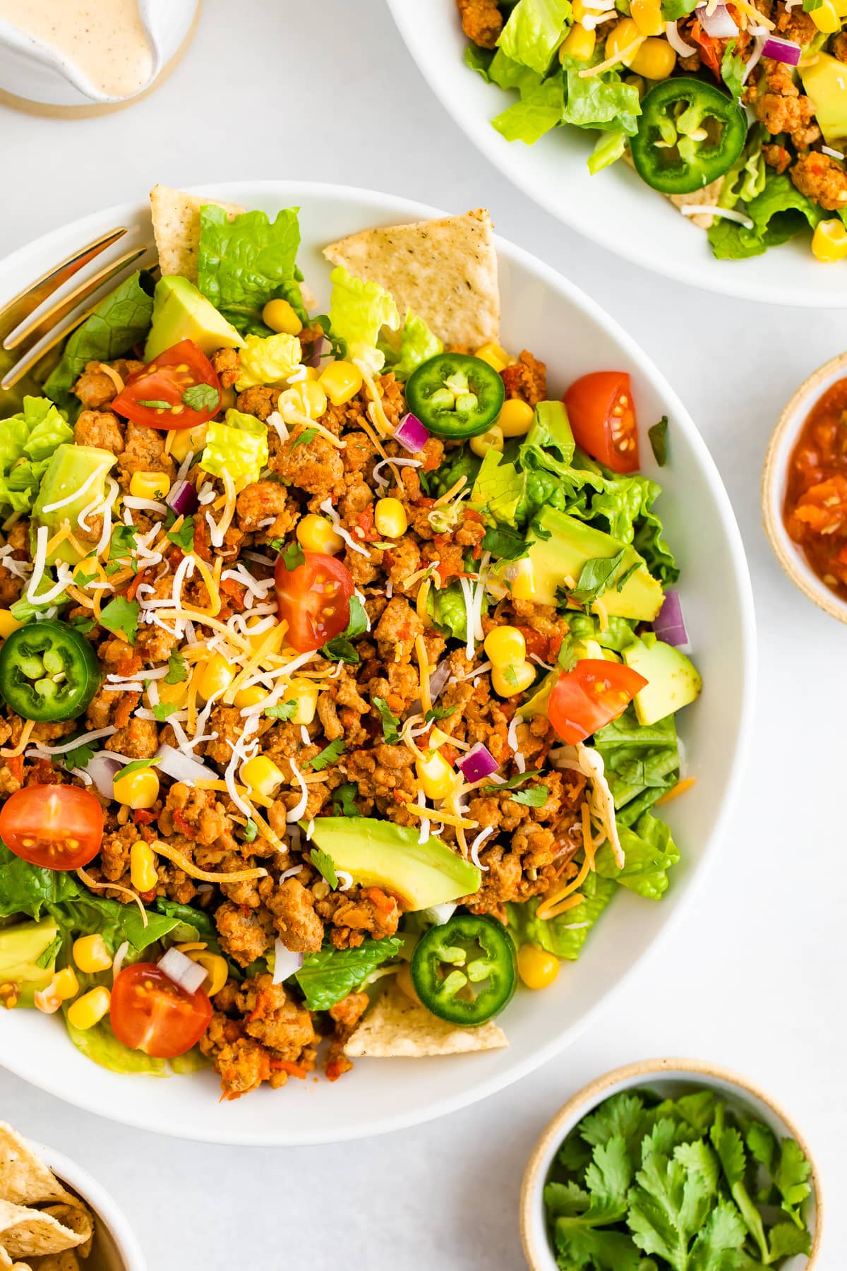 Taco salad topped with ground turkey, avocado, corn, peppers, chips and tomatoes.