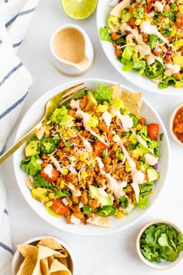 Taco salad topped with ground turkey, avocado, corn, peppers, chips, dressing and tomatoes.