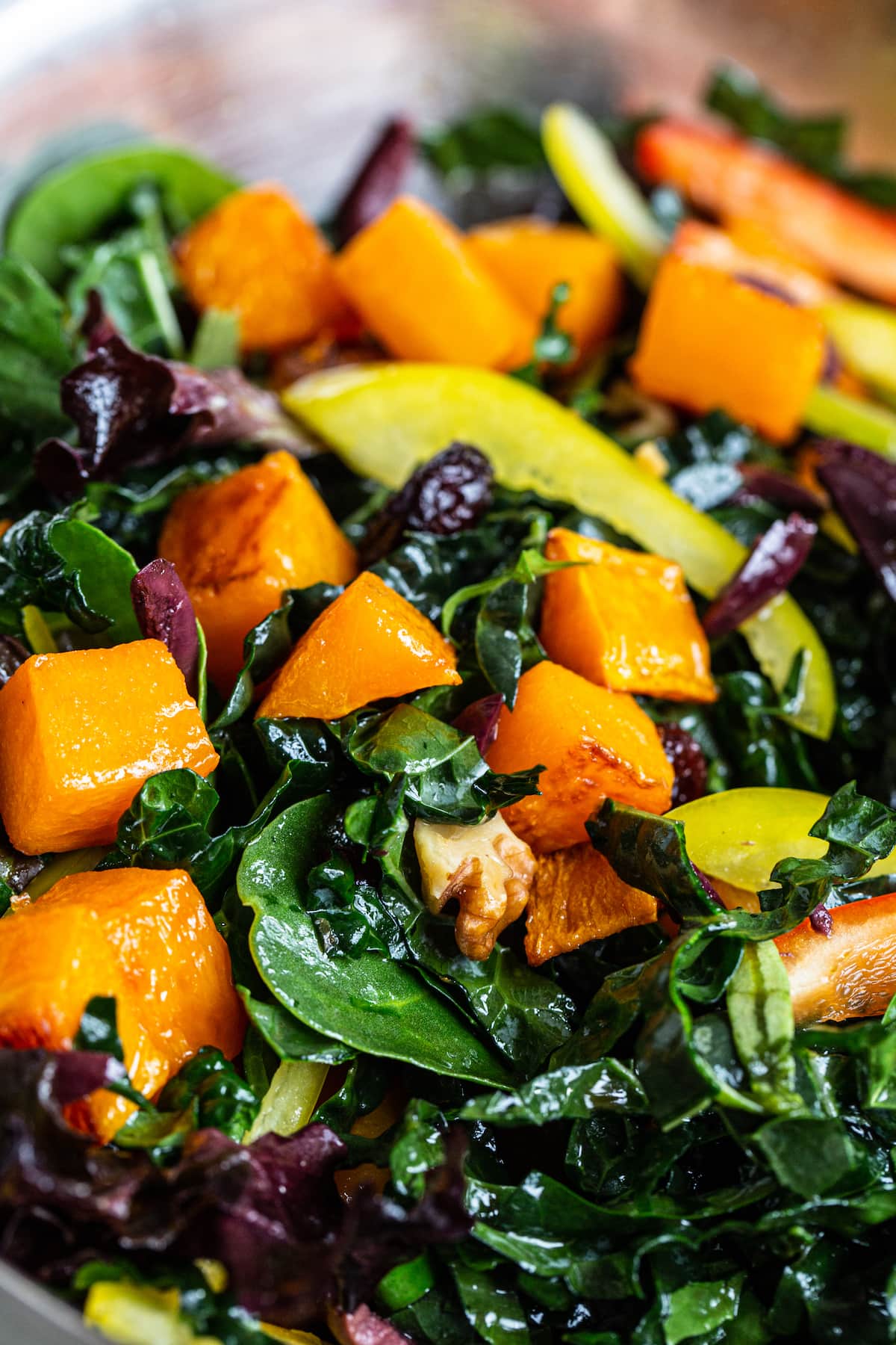 Mixing bowl with kale, butternut squash, walnuts and peppers.