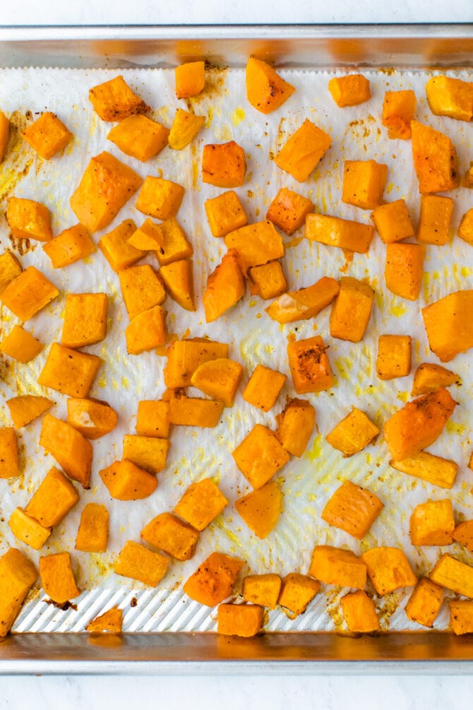 Cubes of roasted butternut squash on a sheet pan.