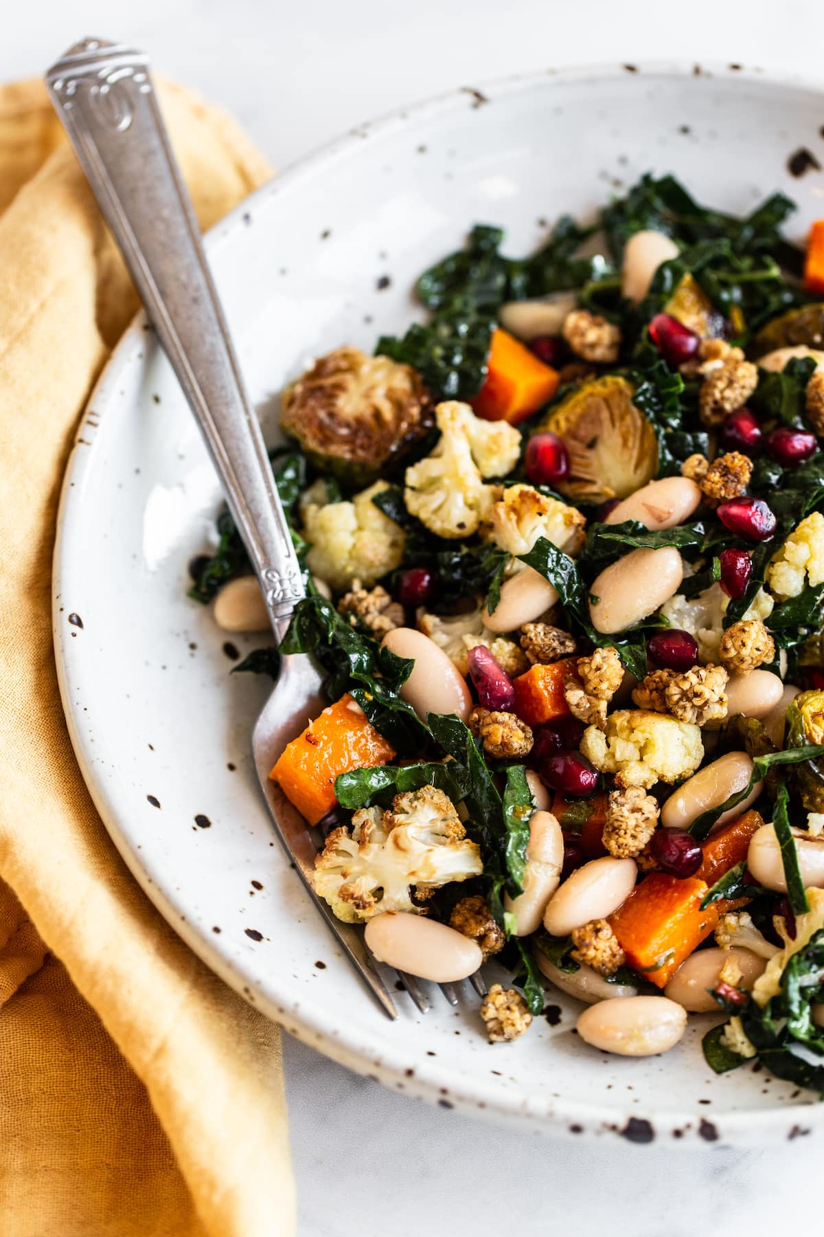 Bowl and fork with a roasted vegetable kale salad.