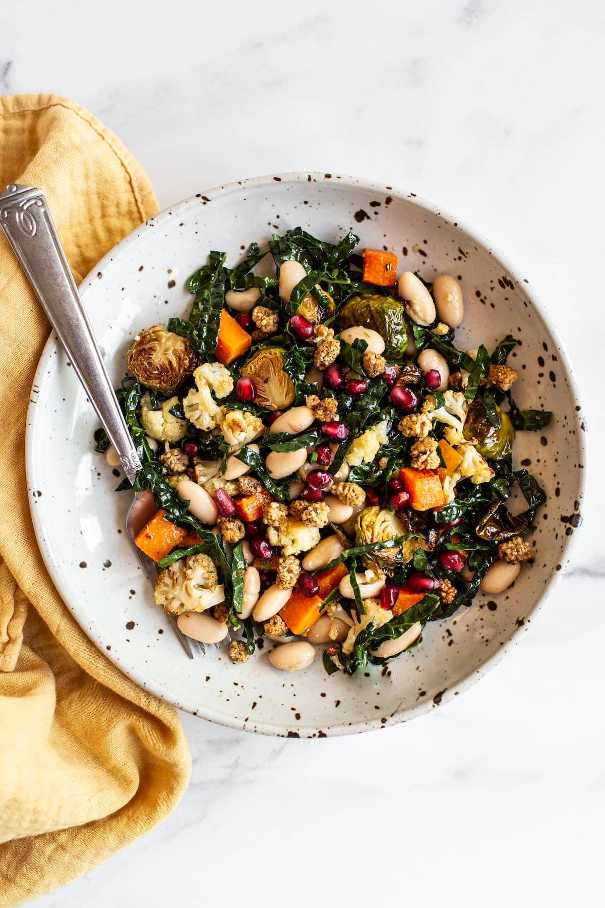 Bowl with roasted vegetable salad with kale and beans.