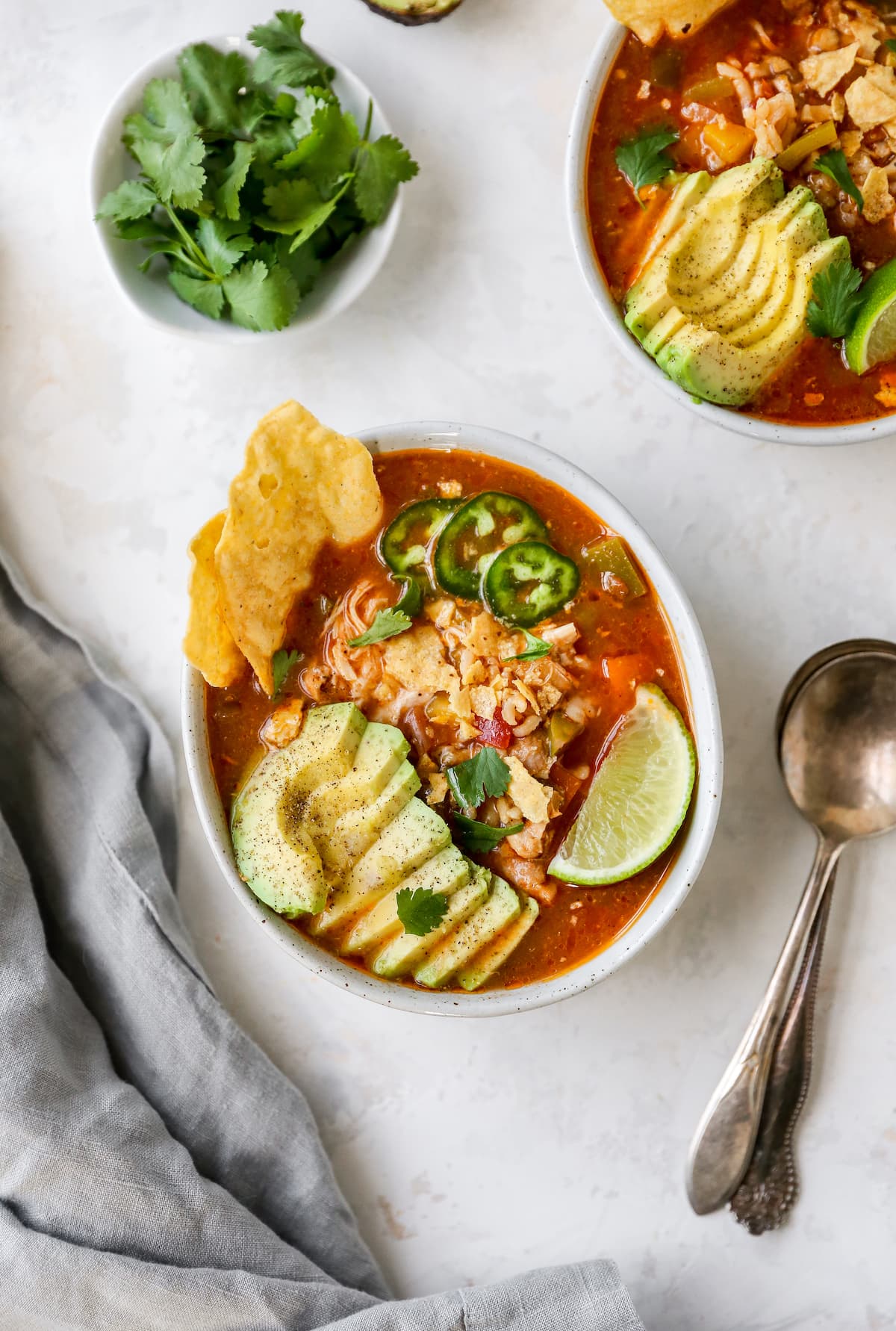 Bowl of chicken fajita topped with avocado, lime, jalapeno and chips.