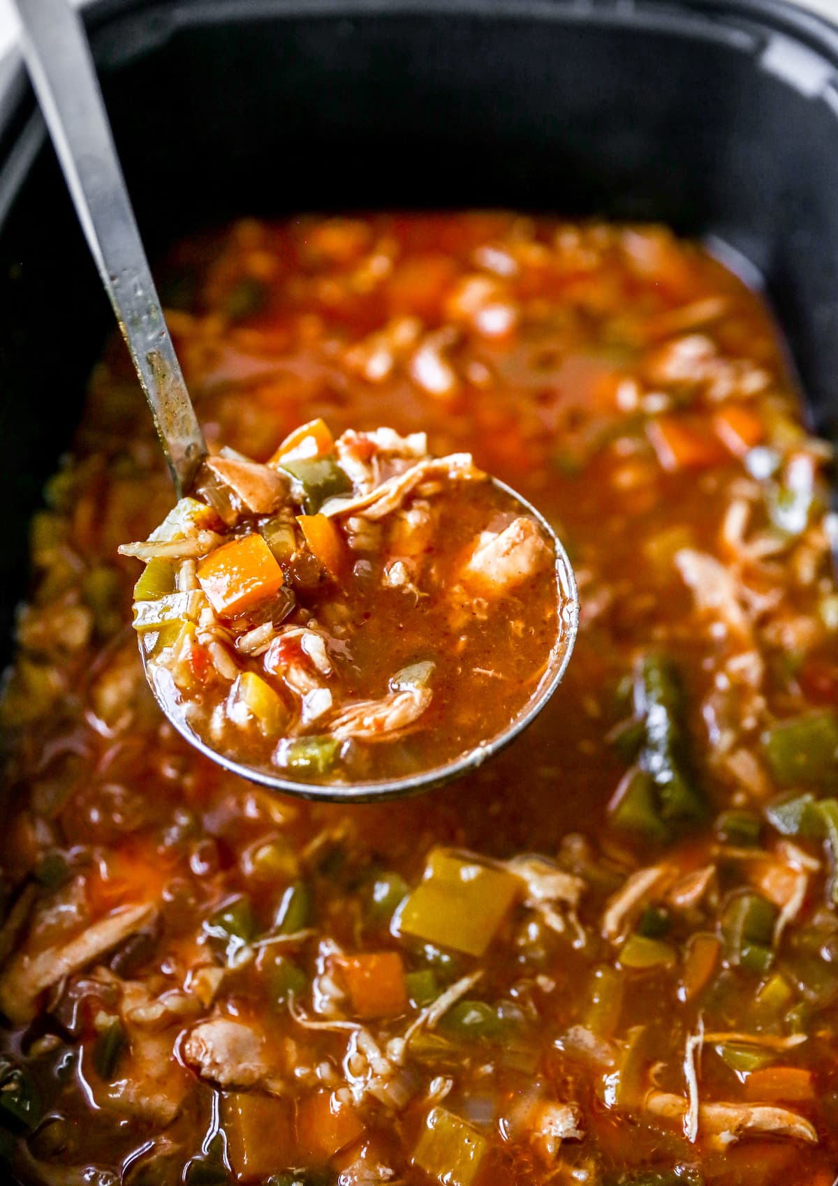 Ladle scooping up chicken fajita soup from a slow cooker.