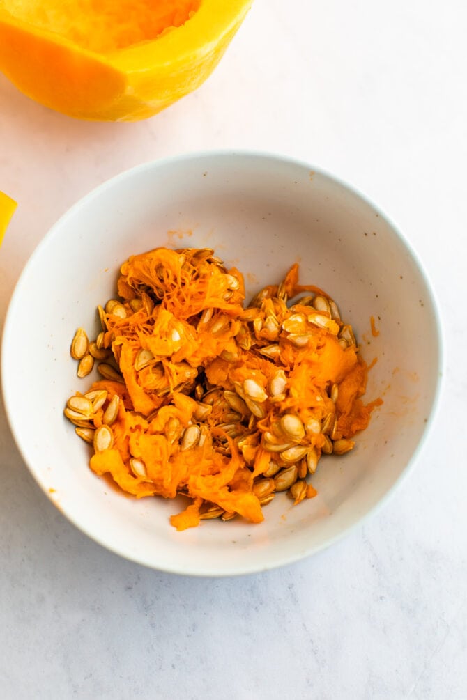 Seeds and guts from a butternut squash in a bowl.