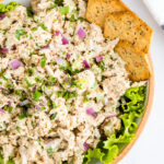 Bowl with tuna salad served over lettuce and served with crackers.