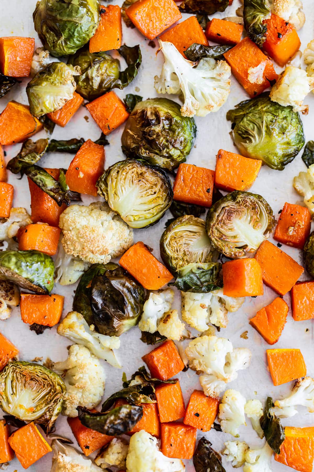 Roasted sweet potatoes, cauliflower and brussels on a sheet pan.
