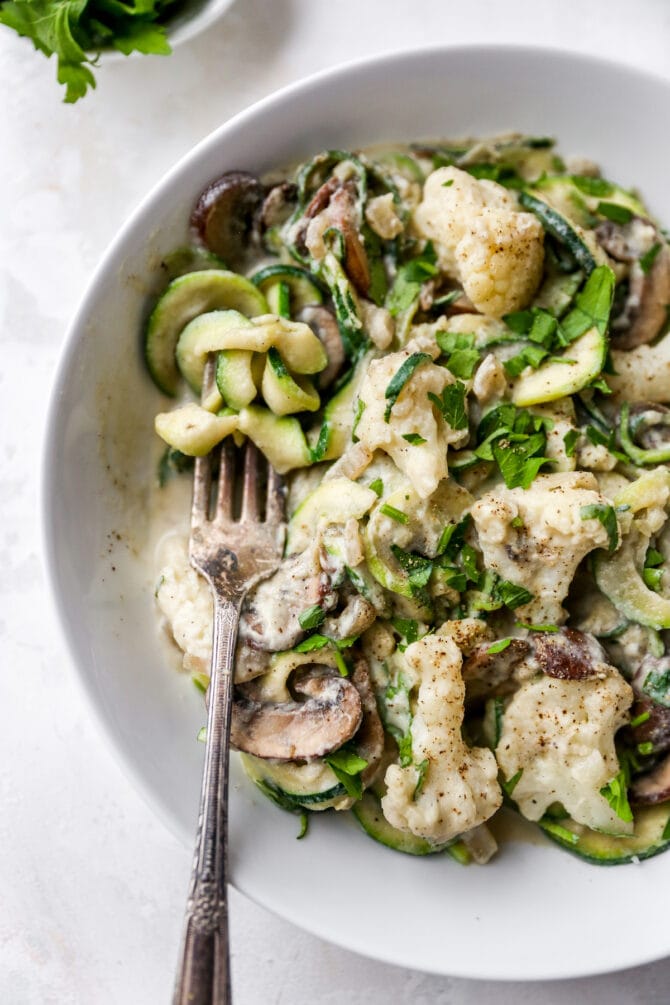 Fork on a plate of zucchini noodle alfredo.