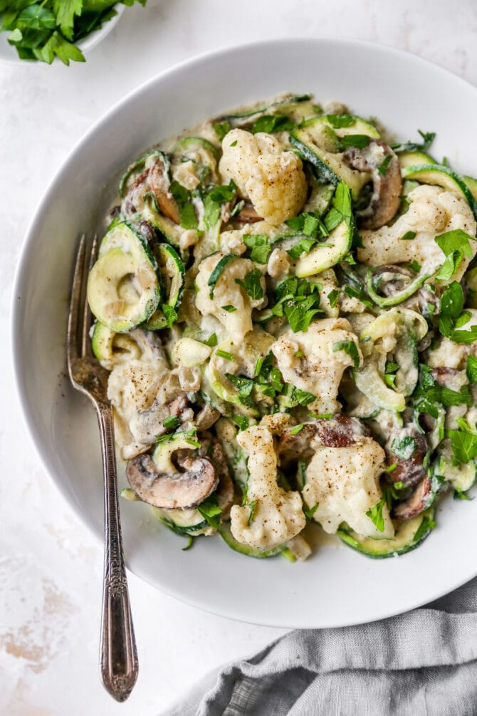 Fork on a plate of zucchini noodle alfredo.