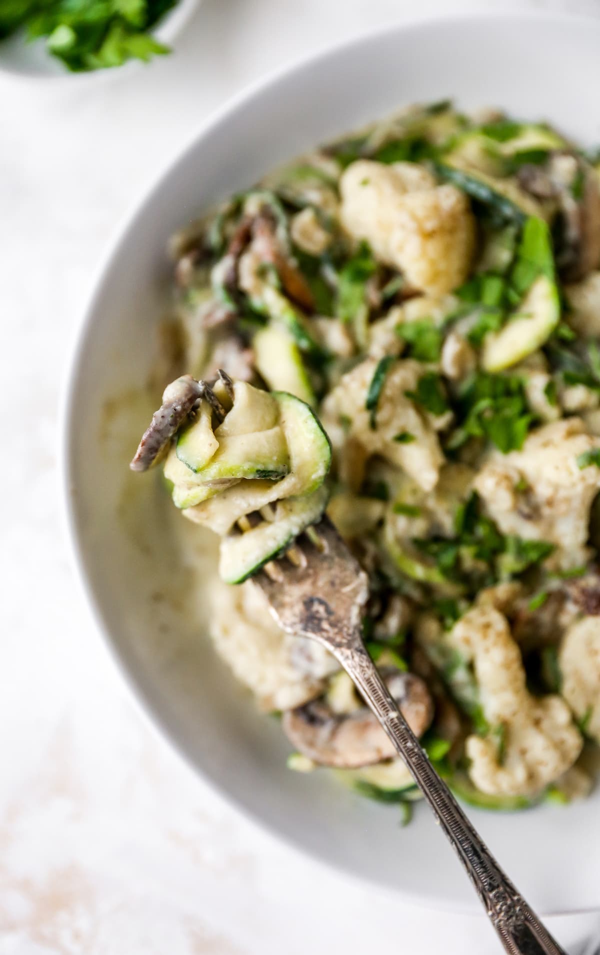 Fork twirling zuchini noodles with alfredo sauce.