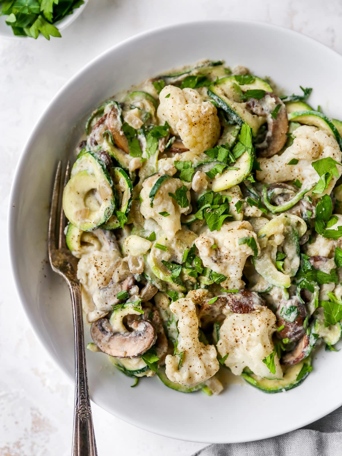 Fork on a plate of zucchini noodle alfredo.