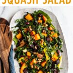 Oval serving tray with kale and butternut salad. Wood salad tongs are beside the plate.