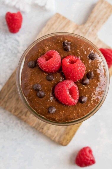Chocolate chia pudding in a jar and topped with mini chocolate chips and raspberries.