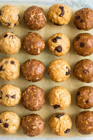 4 types of protein balls on parchment paper, lined up neatly in rows.