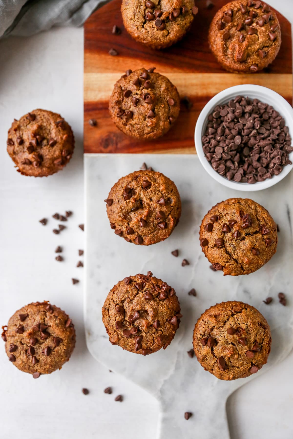 Chocolate chip almond flour muffins on a marble and wood board.