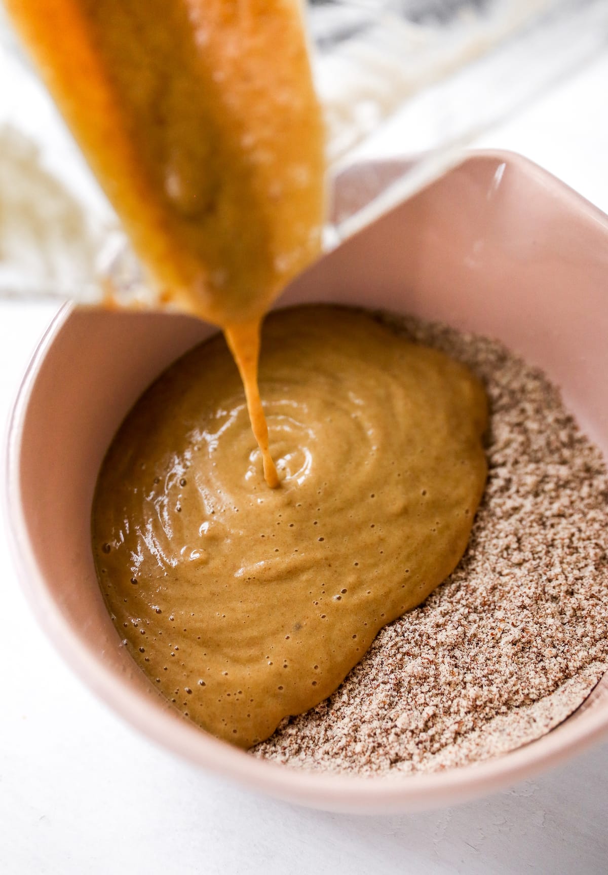 Pouring wet ingredients into a bowl of dry ingredients for making muffins.