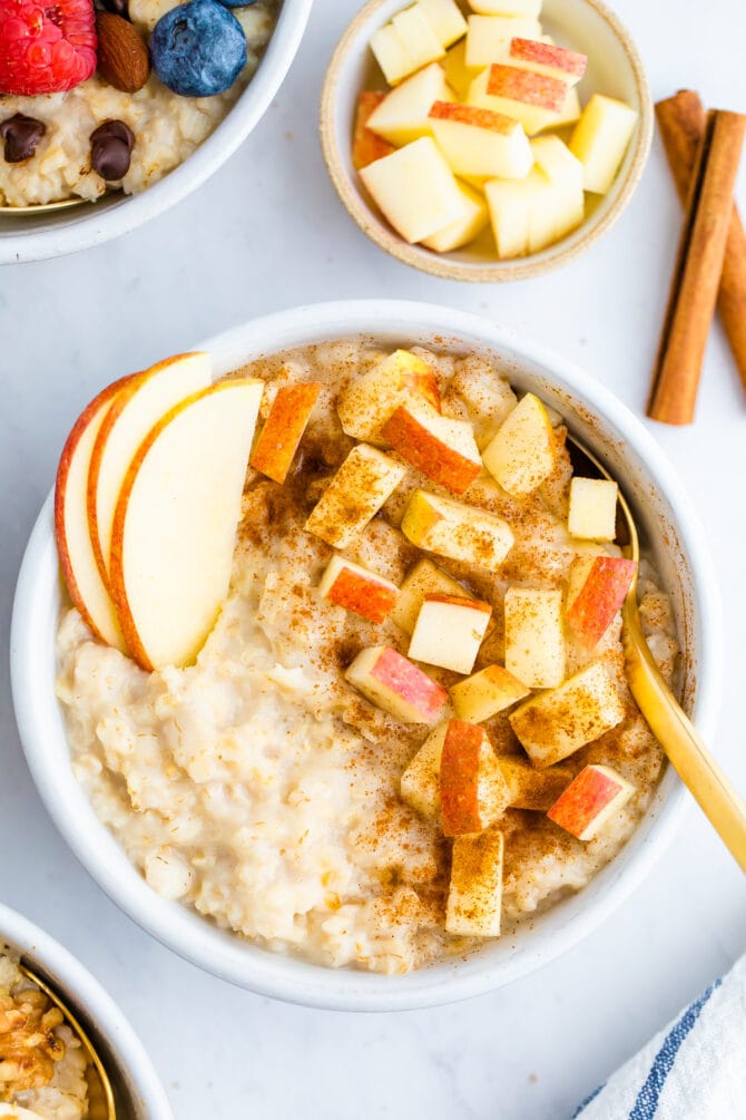 Bowl of oatmeal topped with apples and cinnamon.