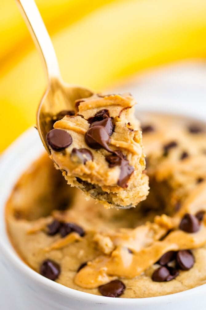 Spoon with a scoop of blended baked oatmeal. Oatmeal is topped with peanut butter and chocolate chips.
