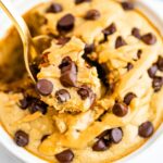 Spoon taking a bite out of chocolate chip and peanut butter topped blended baked oats.
