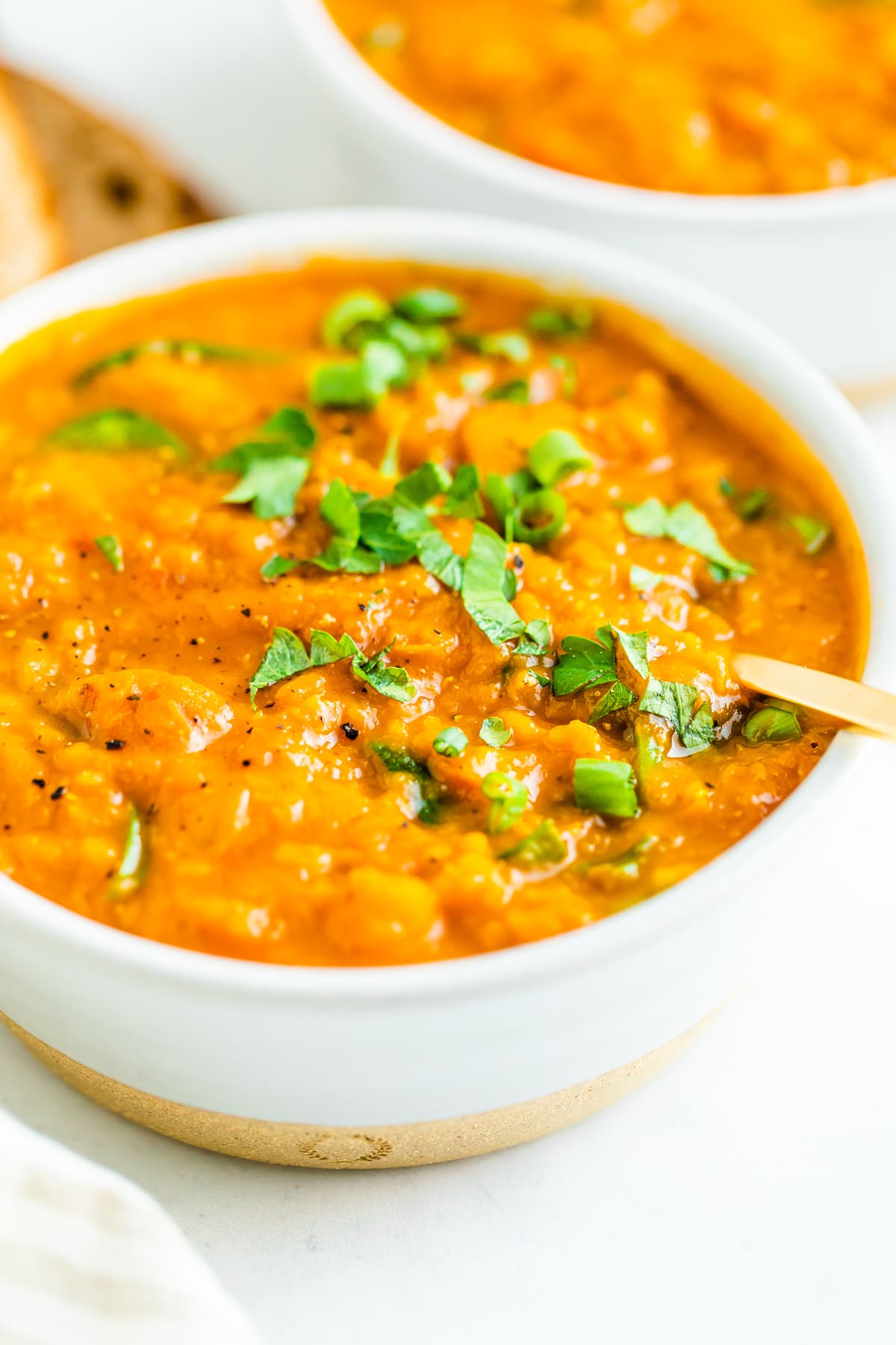 Bowl of butternut squash red lentil strew topped with parsley.