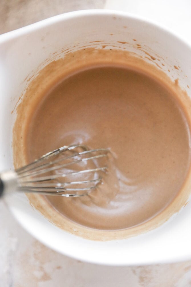 Whisk mixing together creamy balsamic dressing in a bowl.