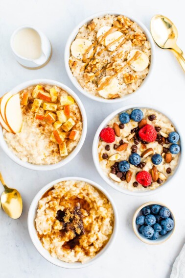 Four bowls of oatmeal with toppings like bananas, nuts, apples, berries, chocolate chips and brown sugar.