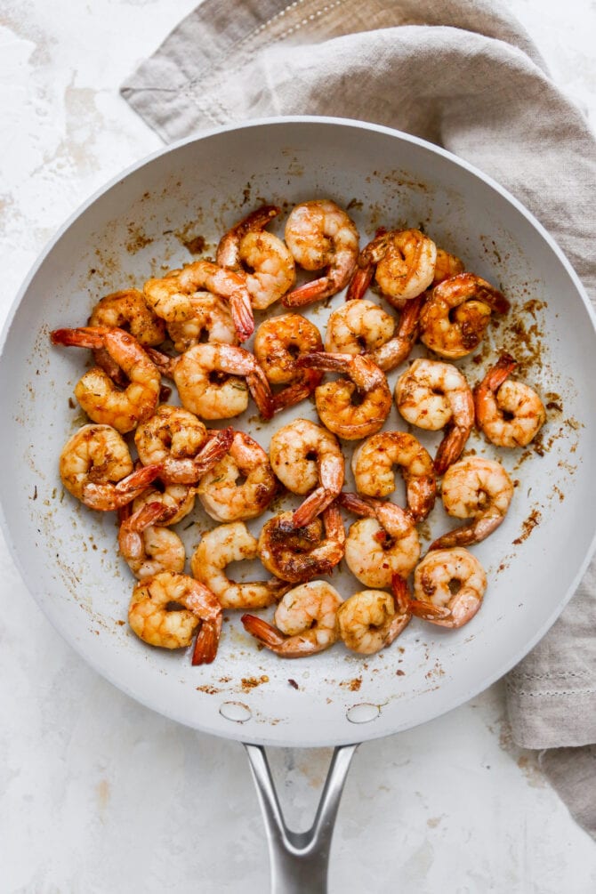 Skillet with sautéed jerk shrimp.