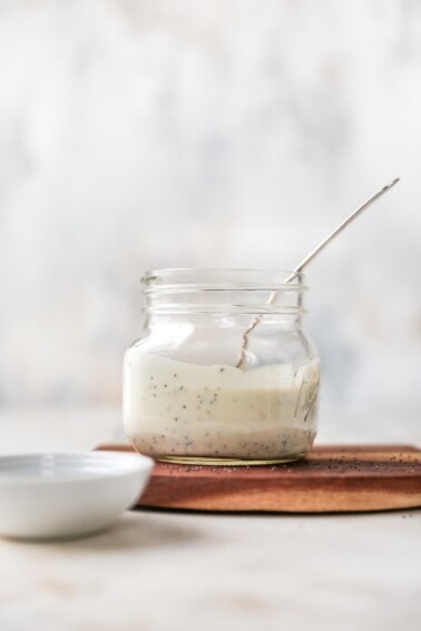 Glass jar and spoon with poppyseed dressing.