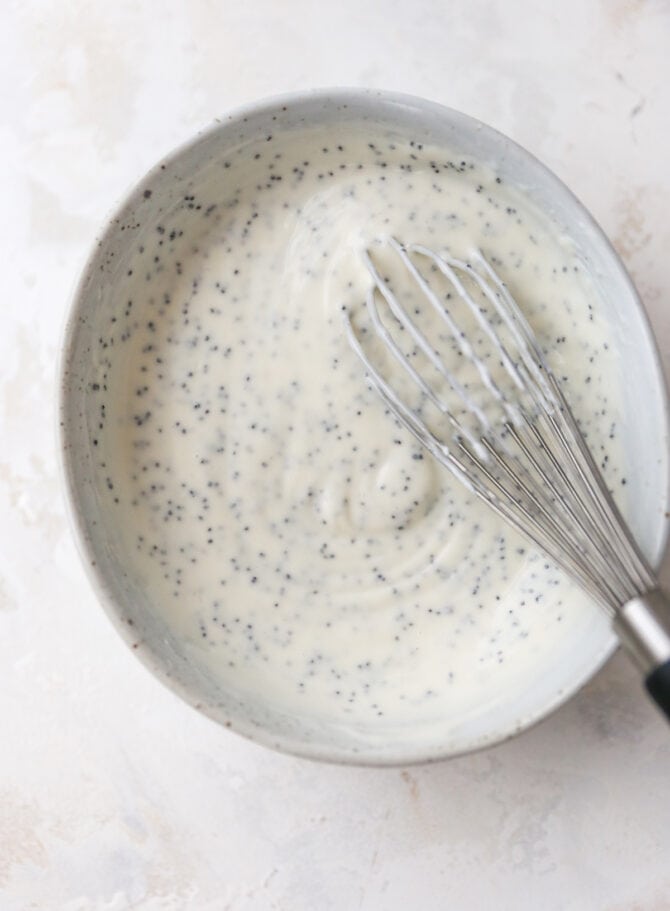 Bowl of poppyseed dressing with a whisk.